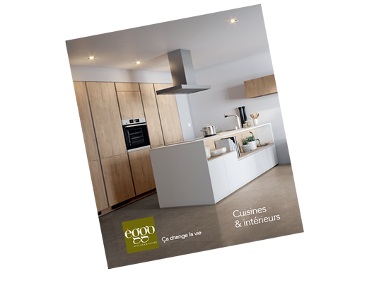 Cuisine moderne avec îlot central blanc, armoires en bois clair, hotte en acier inoxydable et éclairage encastré au plafond.