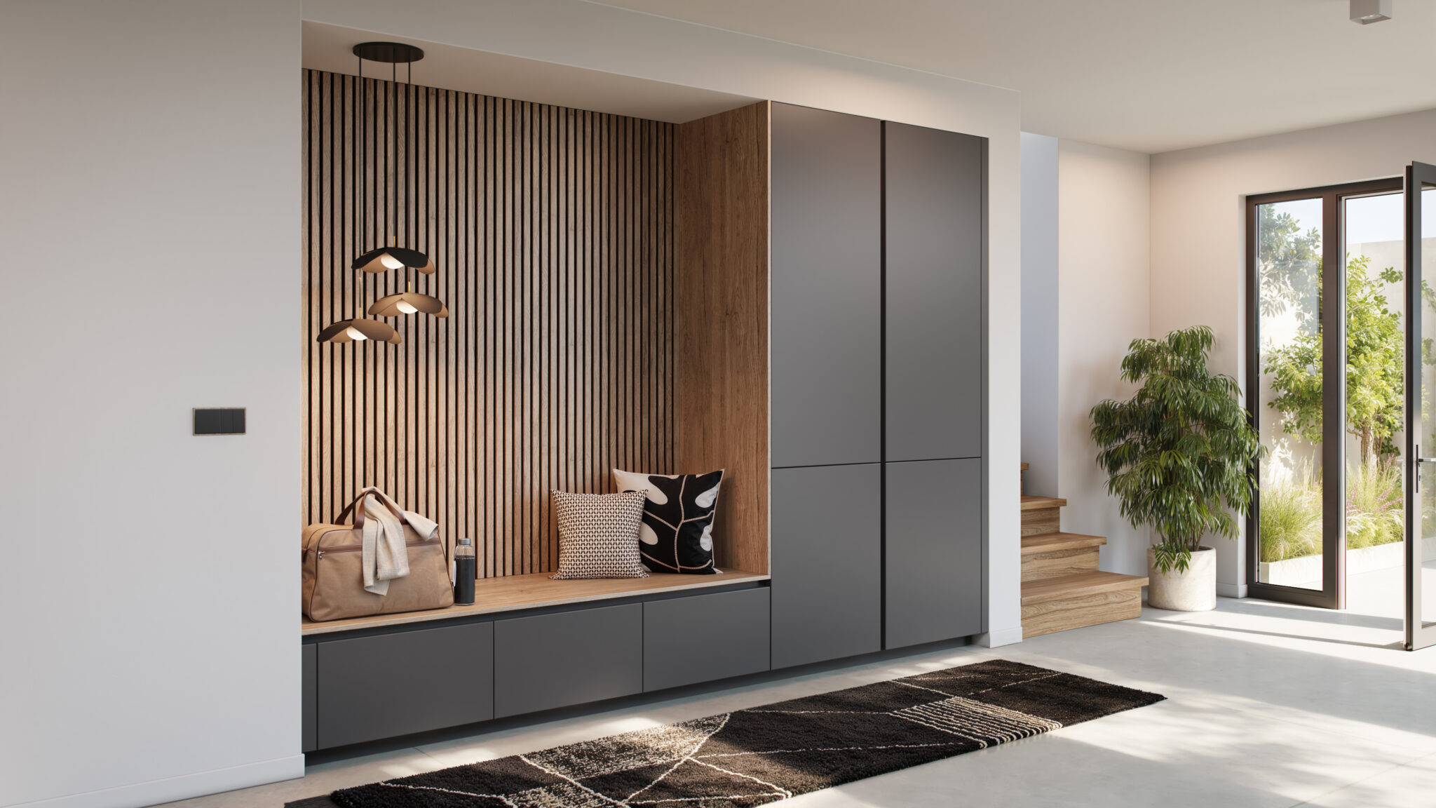 Un espace d'entrée moderne avec des placards gris, un banc en bois, des coussins noirs et blancs, et une plante verte près d'une porte vitrée.